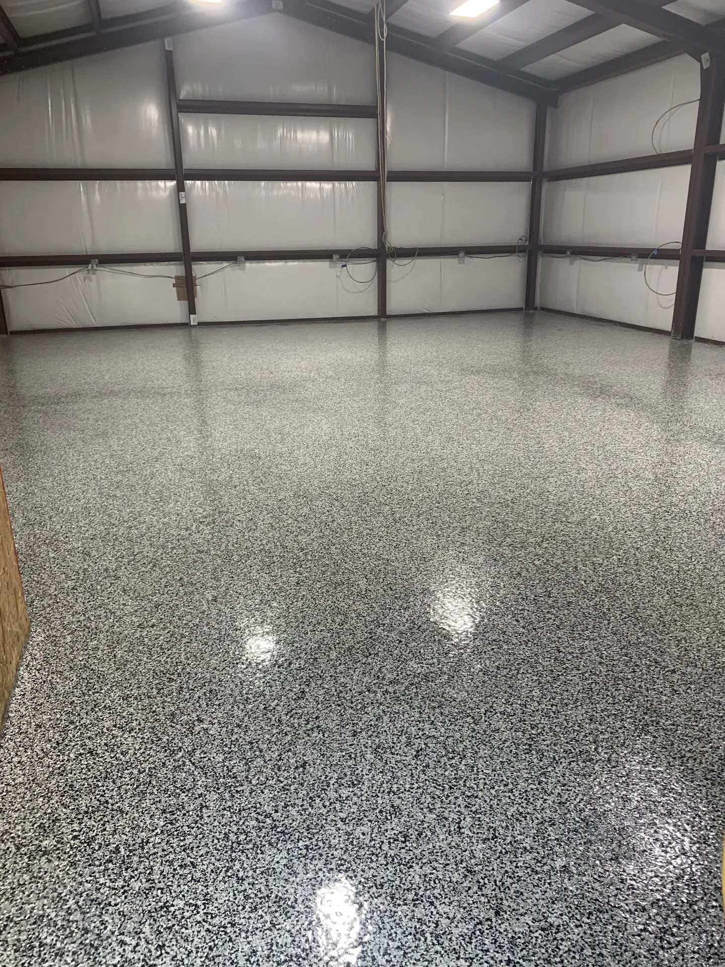 Black and white fleck epoxy floor coating in a warehouse corner